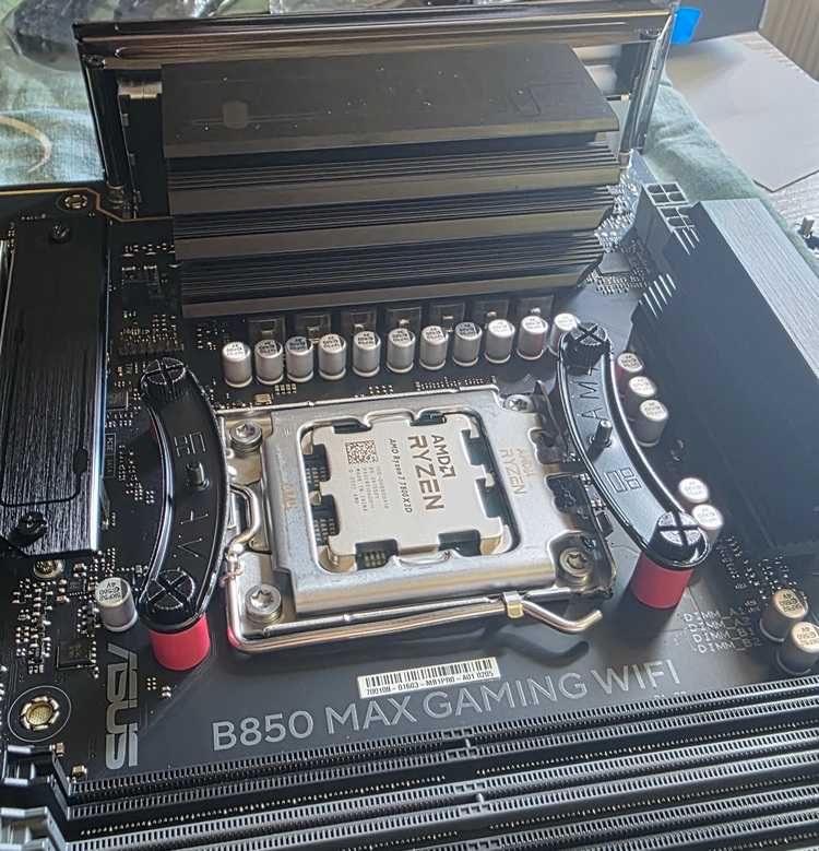 Материнская плата ASUS B850 MAX GAMING WIFI потянет по питанию абсолютно любые 6- и 8-ядерные процессоры (включая все X3D), а также 12- и 16-ядерные модели в игровом режиме или при умеренной рабочей нагрузке. Однако для длительного профессионального рендеринга на флагманских чипах её VRM станет узким местом. Плата оснащена цифровой подсистемой питания по схеме 8+2+1 фазы. На фазах питания ядер (Vcore) используются дискретные (раздельные) MOSFET-транзисторы (Lowside/Highside), прикрытые радиаторами среднего размера. Это типичное бюджетно-среднее решение, которое уступает продвинутым сборкам DrMOS на платах серий TUF или ROG